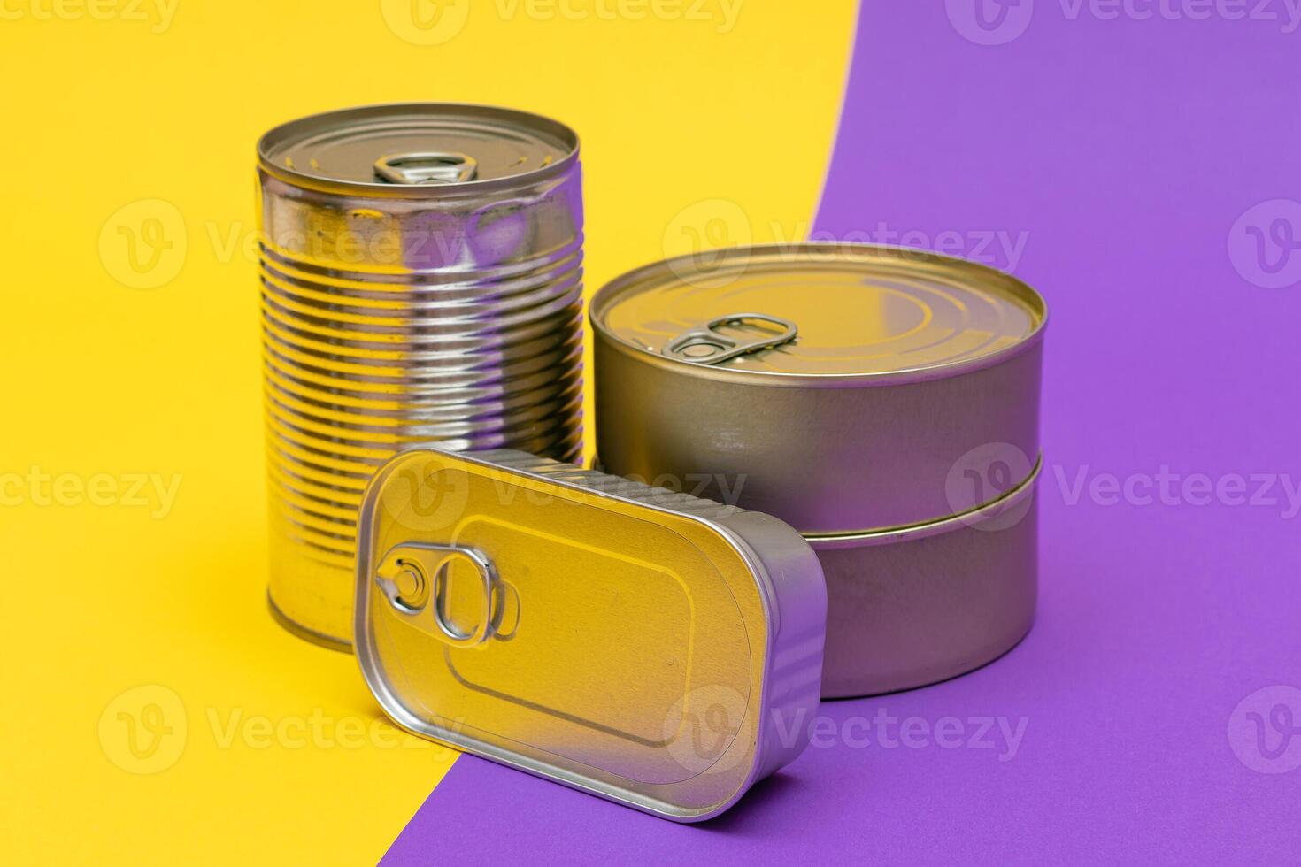 A Group of Stacked Tin Cans with Blank Edges on Split Yellow and Violet Background. Canned Food. Different Aluminum Cans for Safe and Long Term Storage of Food. Steel Sealed Food Storage Containers photo