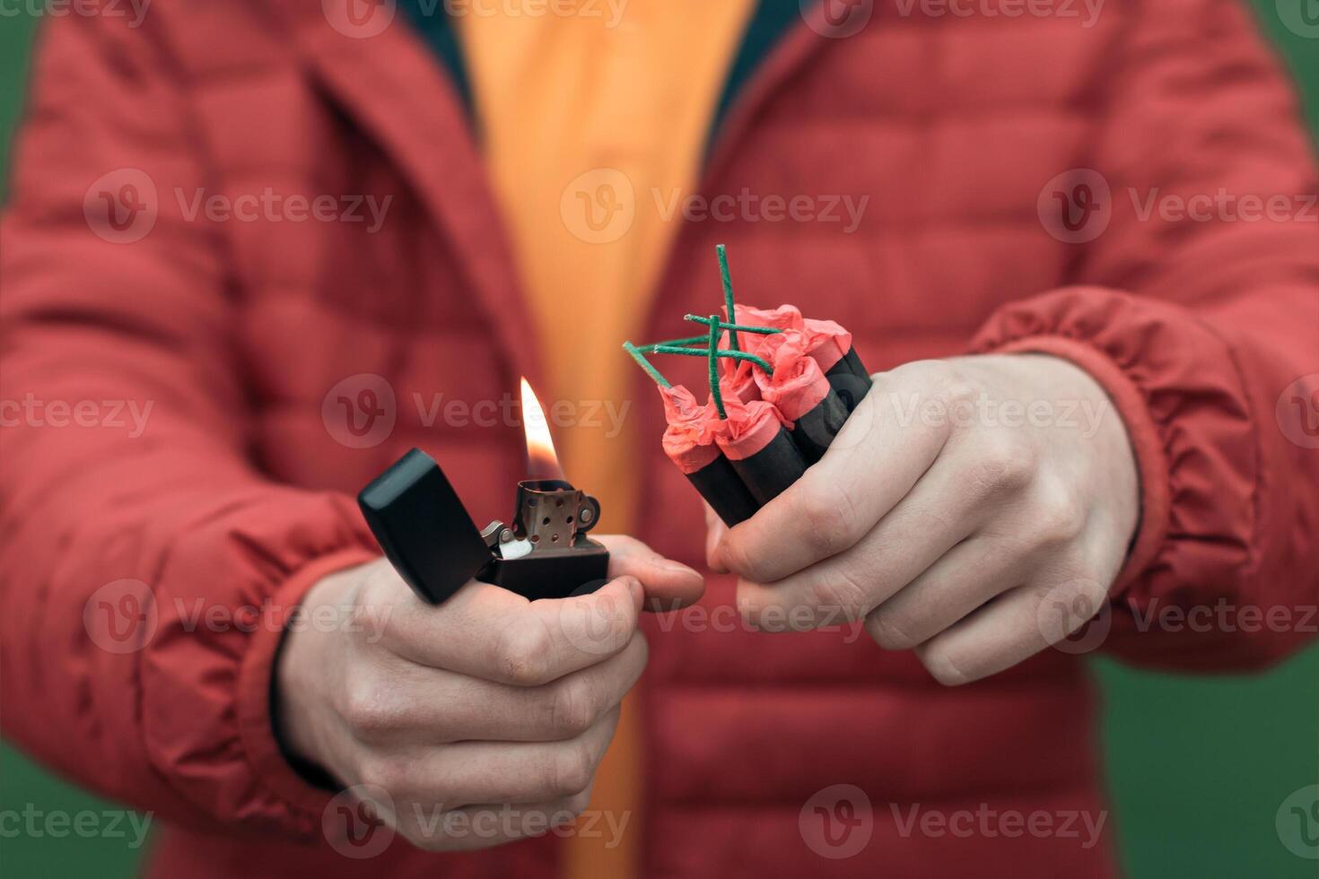 Man in Red Jacked Lighting Up Several Firecrackers in his Hand Using Gasoline Lighter. Guy Getting Ready for New Year Fun with Fireworks or Pyrotechnic Products photo