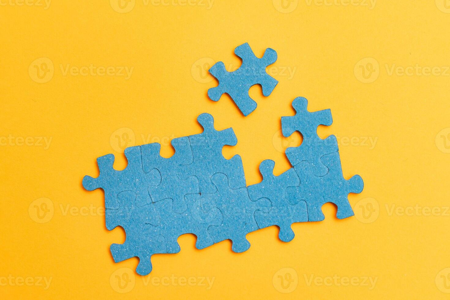 Top View of a Blue Puzzle Pieces Lie on the Yellow Background photo