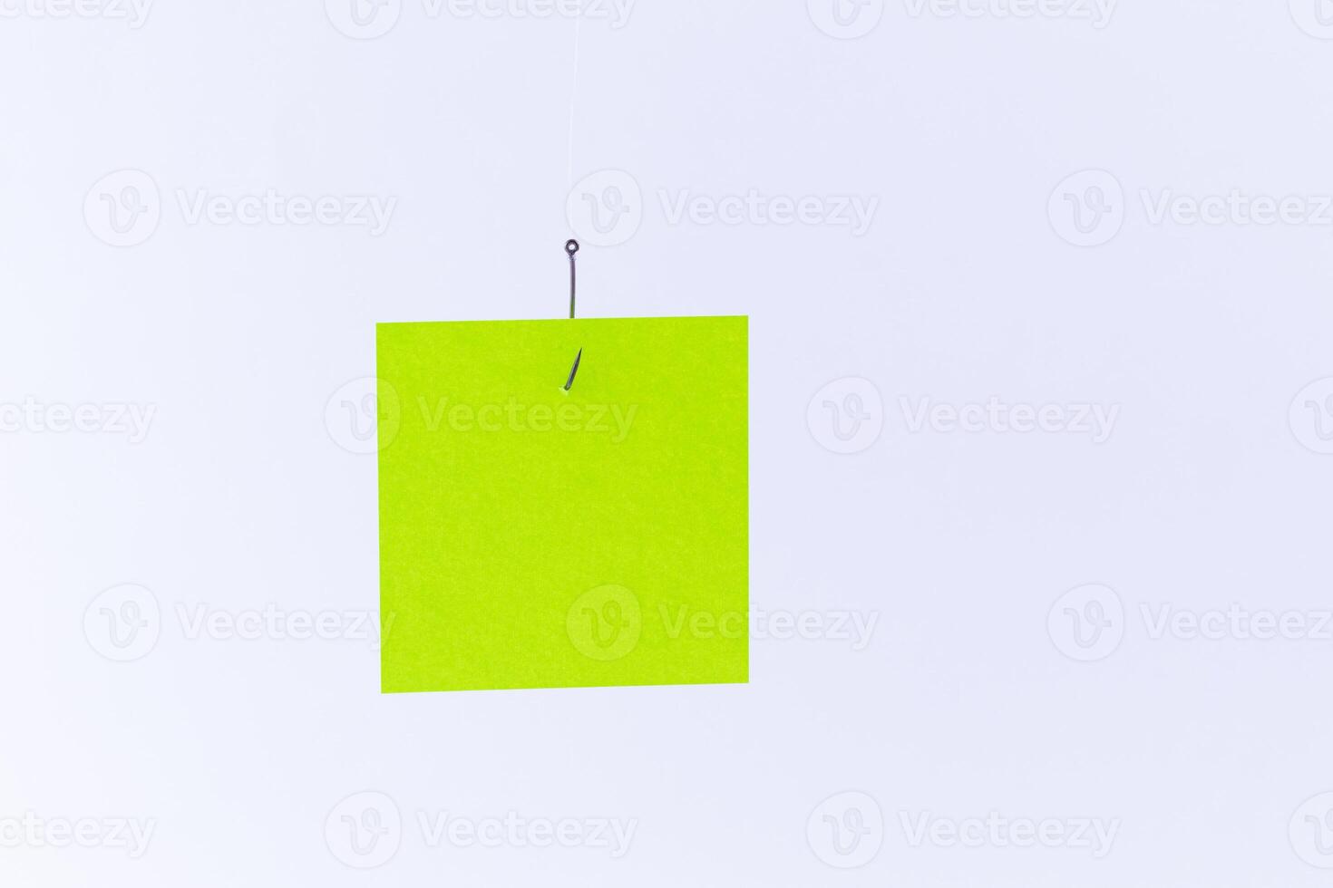 Mockup of a Blank Green Memo Paper with Copy Space Hanging on a Fishing Hook Against the White Background. Reminder or To Do List. Sticky Note Template photo