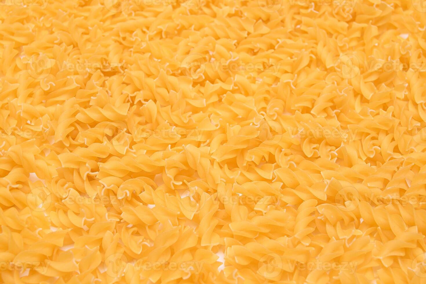 Uncooed Fusilli Pasta - Background. Texture of Bright Golden Dry Macaroni photo