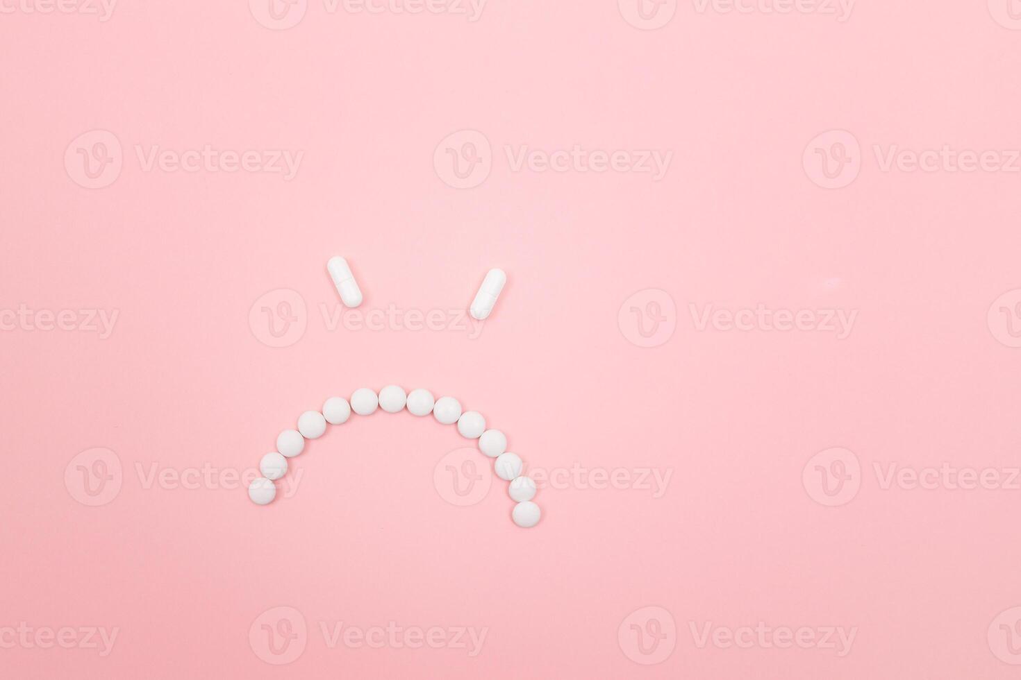 Pharma Harm. Angry Smiley Face Made from White Pills, Lying on Pink Backgrond. Global Pharmaceutical Industry and Medicinal Products photo