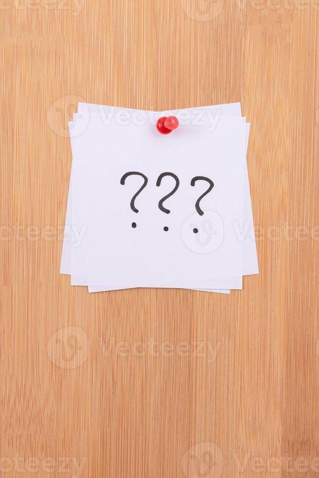 White Sticky Notes with Three Question Marks Pinned to the Wooden Message Board. To Do List Reminder in the Office. Memo Note at Work photo