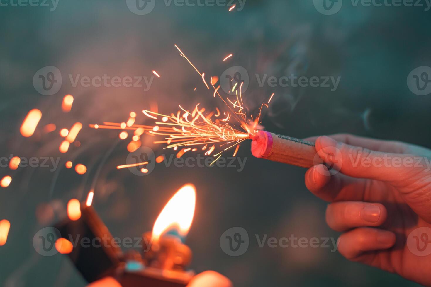 Young Man Lighting Up Firecracker in his Hand Using Gasoline Lighter. Guy Getting Ready for New Year Fun with Fireworks or Pyrotechnic Products - CloseUp Shot, Rear View photo