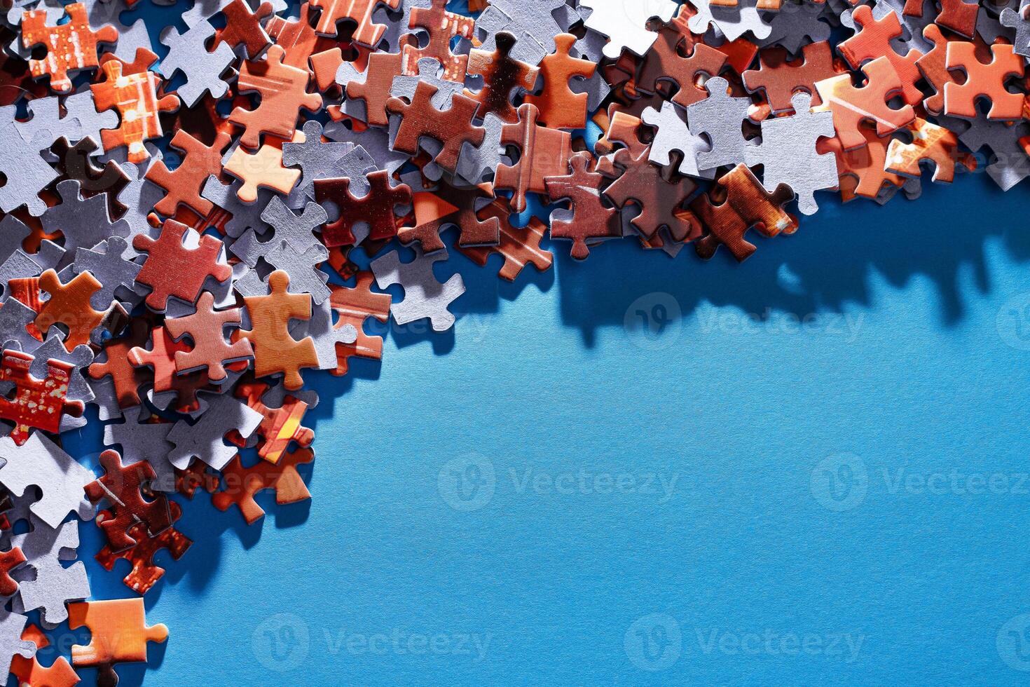 Mixed Pieces of a Colorful Jigsaw Puzzle Lie on the Blue Background With Copy Space - Strategy and Solving Problem Concept photo