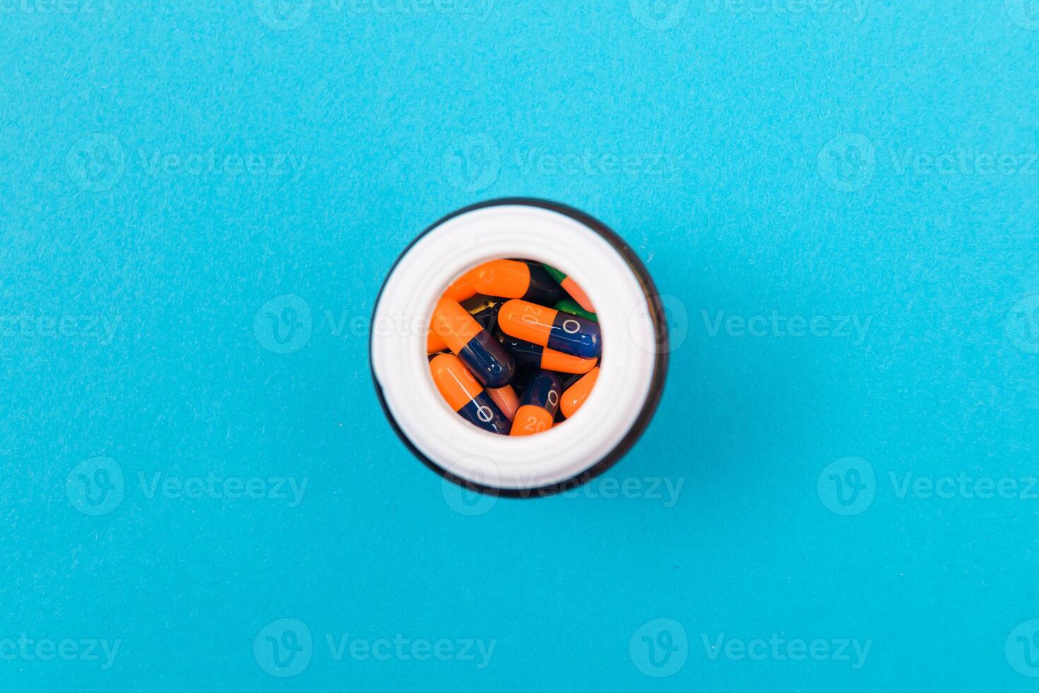 Global Pharmaceutical Industry and Medicinal Products - Different Colored Pills, Tablets and Capsules in Bottle Lying on Blue Background. Copy Space, Top View, Flat Lay photo