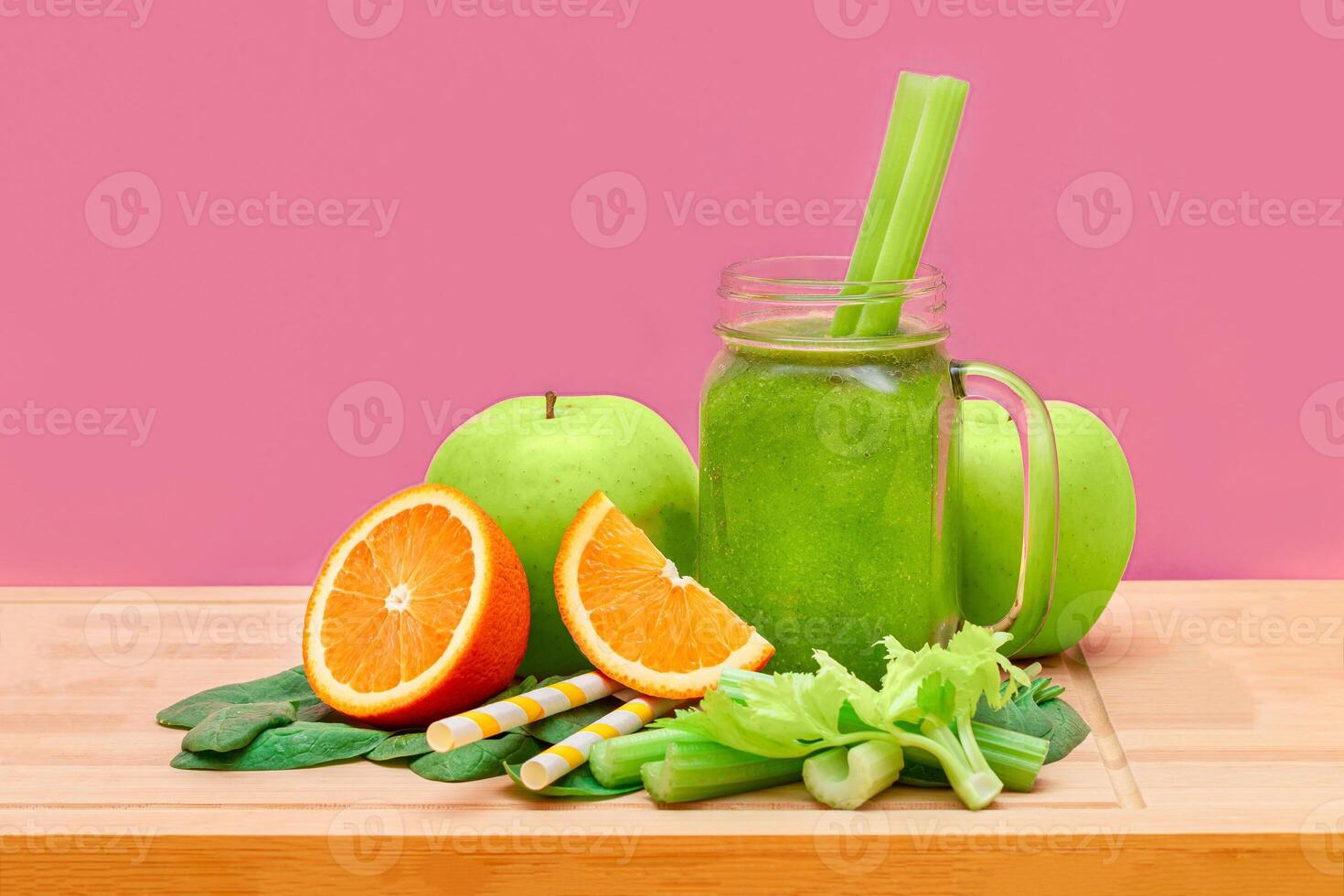 Fresh Green Smoothie of Apple, Celery, Spinach and Orange in Glass Smoothie Jar with Yellow Cocktail Straw on Wooden Cutting Board. Vegan Detox Drink. Vegetarian Culture. Healthy Eating and Fruit Diet photo