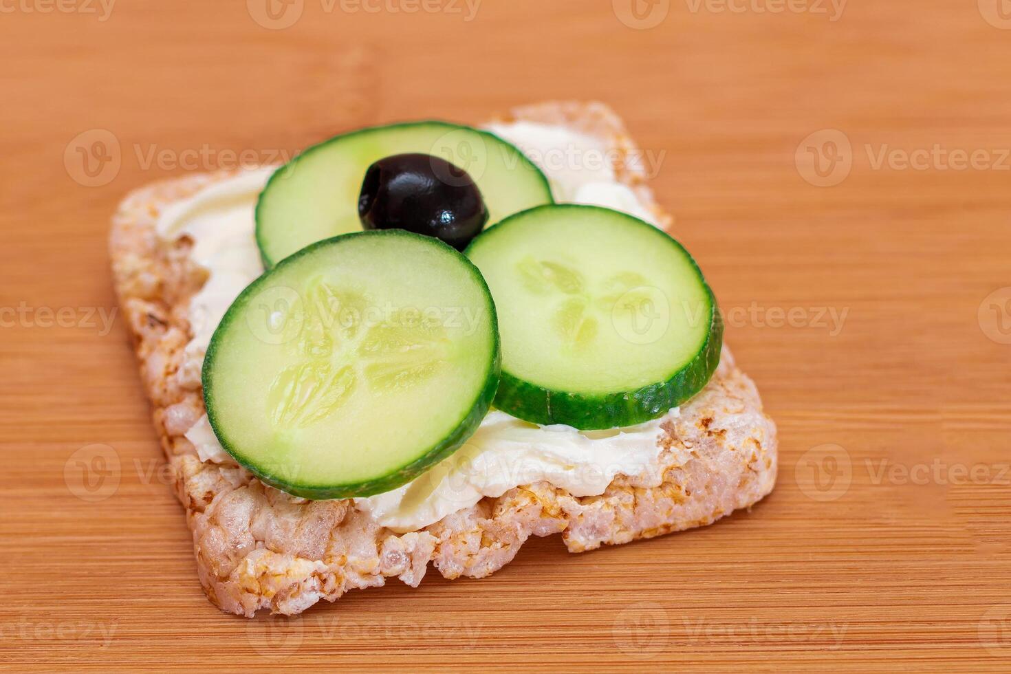 Rice Cake Sandwich with Fresh Cucumber, Cream Cheese and Olives on Bamboo Cutting Board. Easy Breakfast. Diet Food. Quick and Healthy Sandwiches. Crispbread with Tasty Filling. Healthy Dietary Snack photo