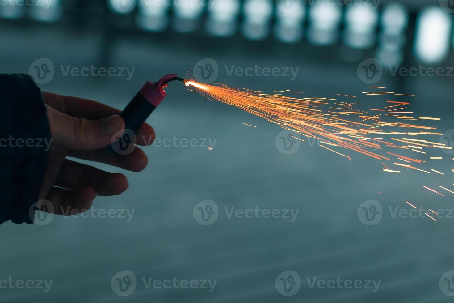 Burning Firecracker with Sparks. Guy Holding a Petard in a Hand. Loud and Dangerous New Year's Entertainment. Hooliganism with Pyrotechnics. Noise of Firecrackers in Public Places photo