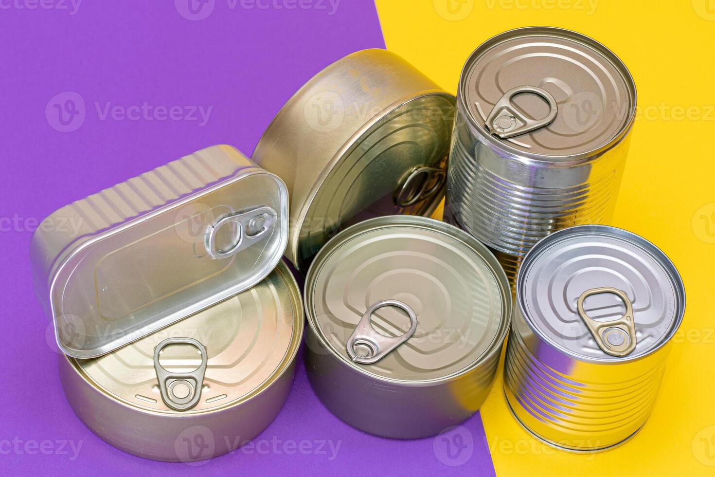A Group of Stacked Tin Cans with Blank Edges on Split Yellow and Violet Background. Canned Food. Different Aluminum Cans for Safe and Long Term Storage of Food. Steel Sealed Food Storage Containers photo