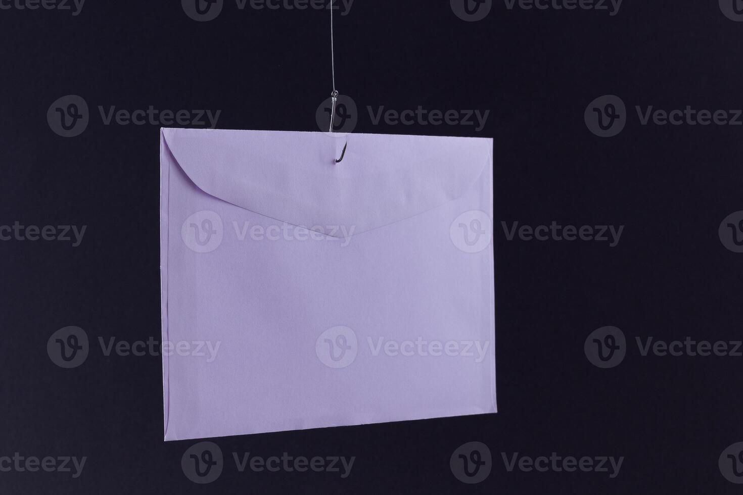 Violet Envelope Hanging on a Fishing Hook Against the Black Background photo