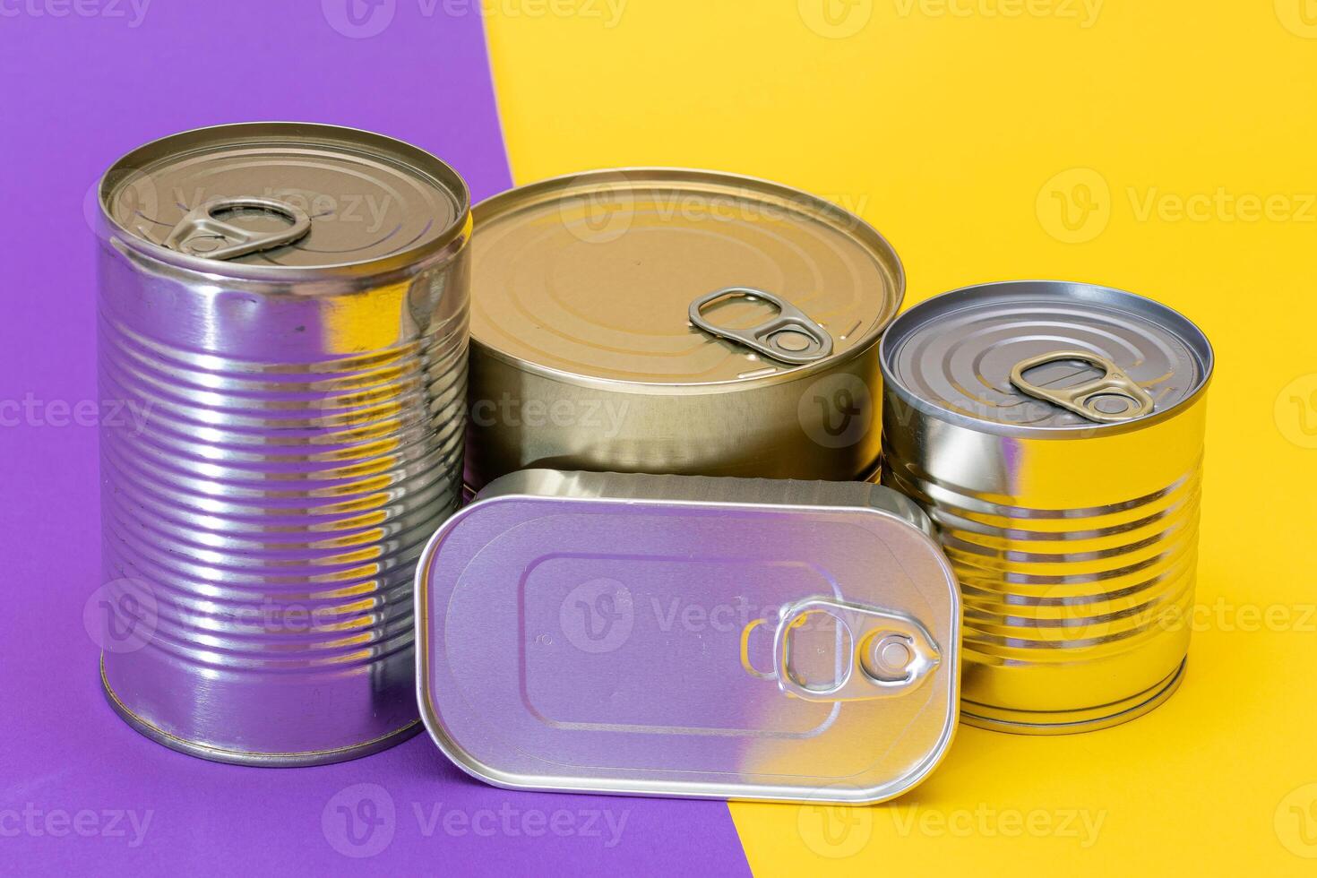 A Group of Stacked Tin Cans with Blank Edges on Split Yellow and Violet Background. Canned Food. Different Aluminum Cans for Safe and Long Term Storage of Food. Steel Sealed Food Storage Containers photo