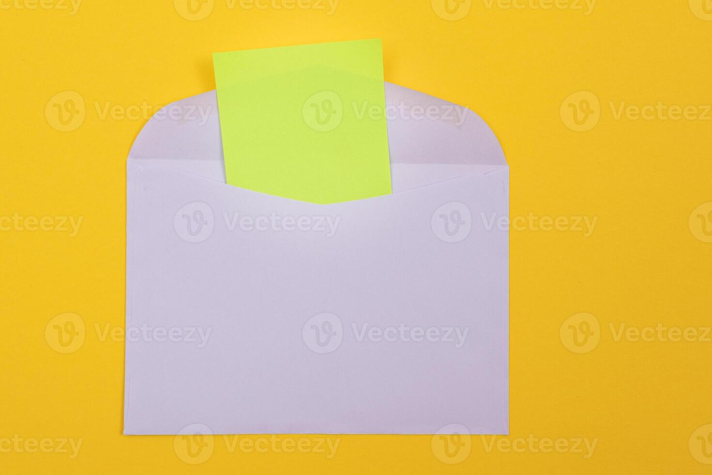 Violet Envelope with Blank Green Sheet of Paper Inside, Lying on Yellow Background - Mock Up with Copy Space. Receiving Mail or Notice, Sending Postcard - Top View, Flat Lay photo