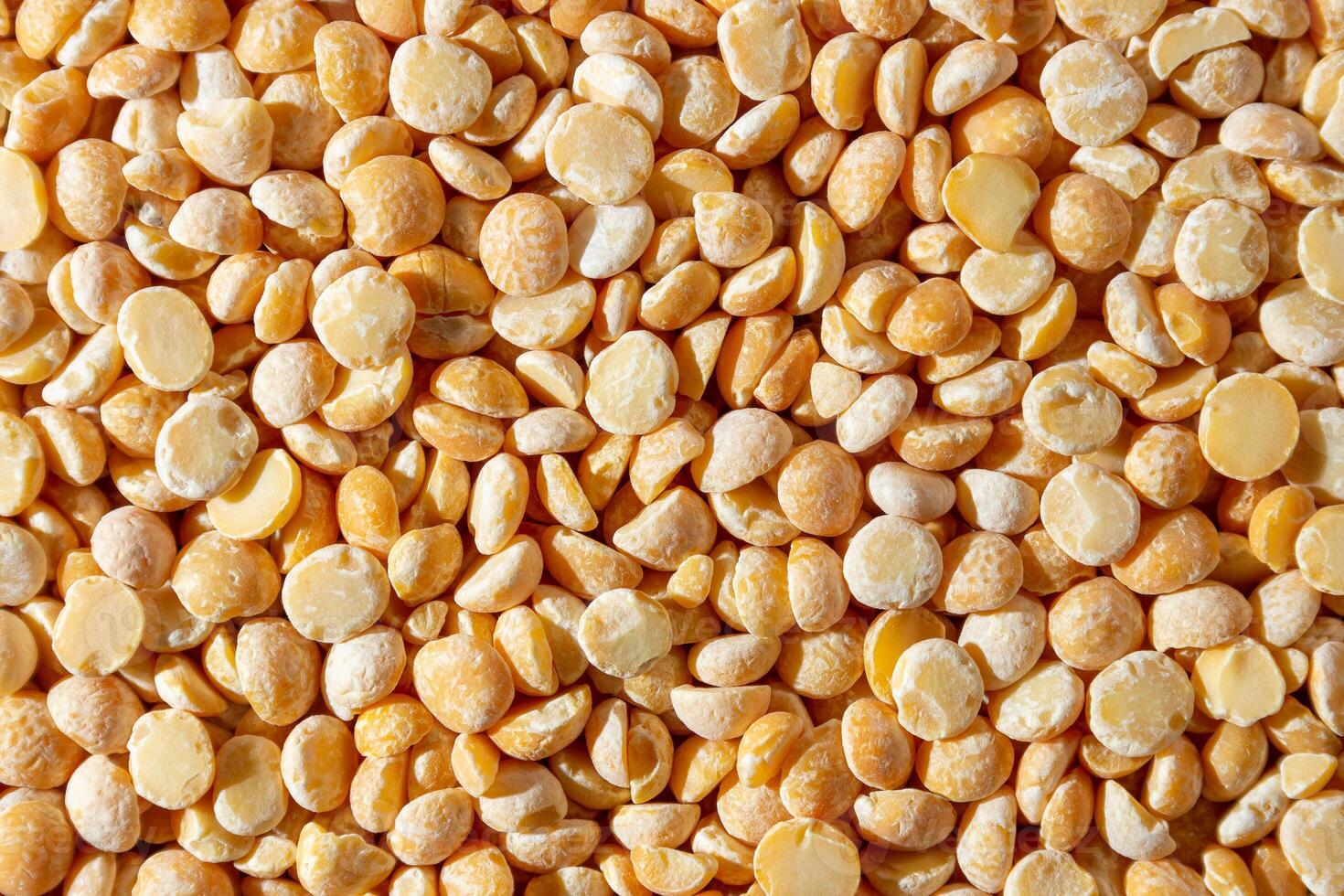 Uncooked Polished Split Peas Background. A Culinary Canvas of Dry Yellow Peas, Creating a Lively and Textured Background for Gourmet Cooking. Scattered Raw Polished Peas. Healthy Eating Ingredients photo