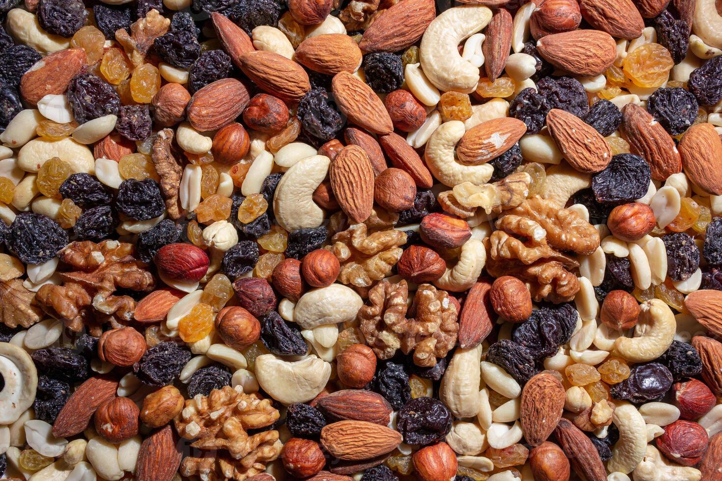 Mixed Nuts. Almonds, Walnuts, Cashews, Peanuts, Hazelnuts, Dried Prunes and Raisins. Different Nut Mix. Background from Various Nuts and Dried Fruits photo