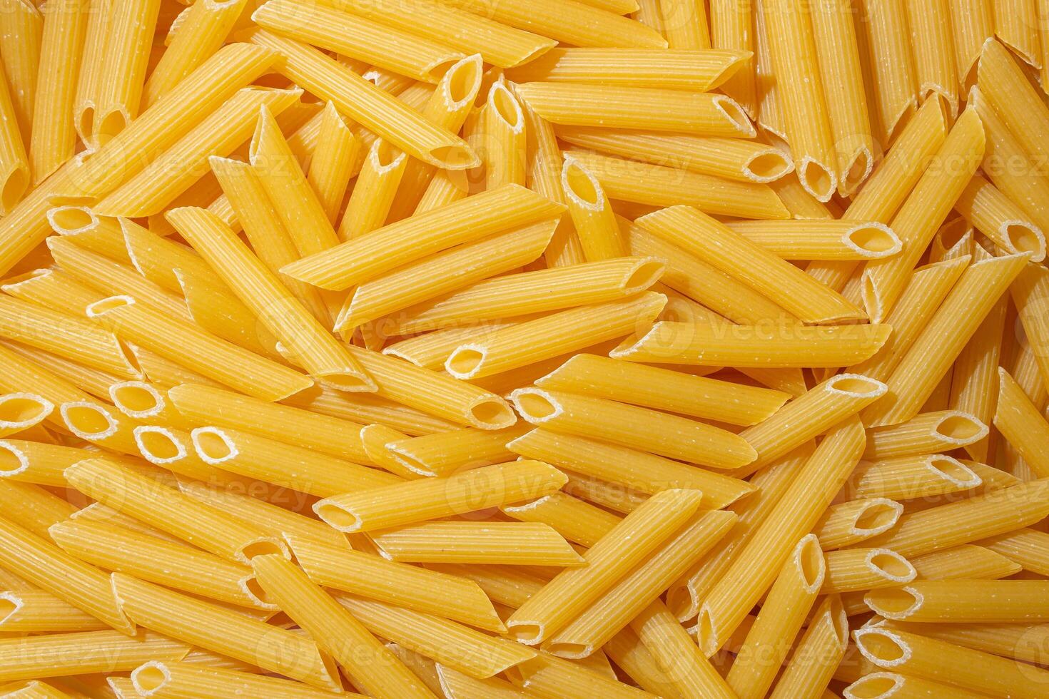 Uncooked Penne Rigate Pasta. A Culinary Canvas of Penne Macaroni, Creating a Lively and Textured Background for Gourmet Cooking. Dry Pasta. Raw Macaroni - Top View, Flat Lay photo