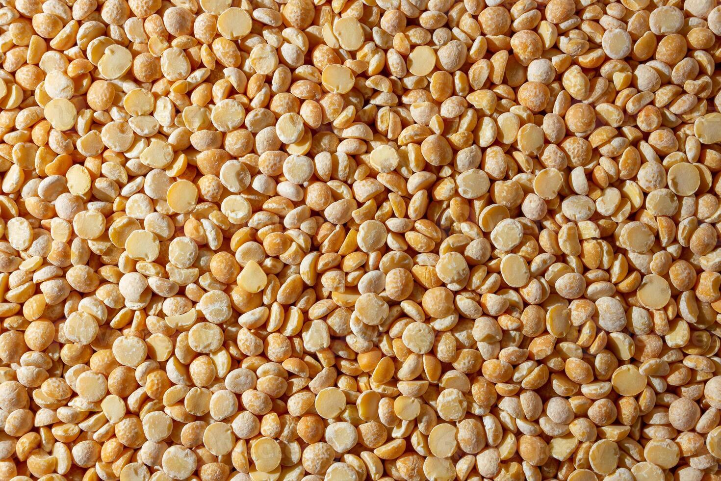 Uncooked Polished Split Peas Background. A Culinary Canvas of Dry Yellow Peas, Creating a Lively and Textured Background for Gourmet Cooking. Scattered Raw Polished Peas. Healthy Eating Ingredients photo