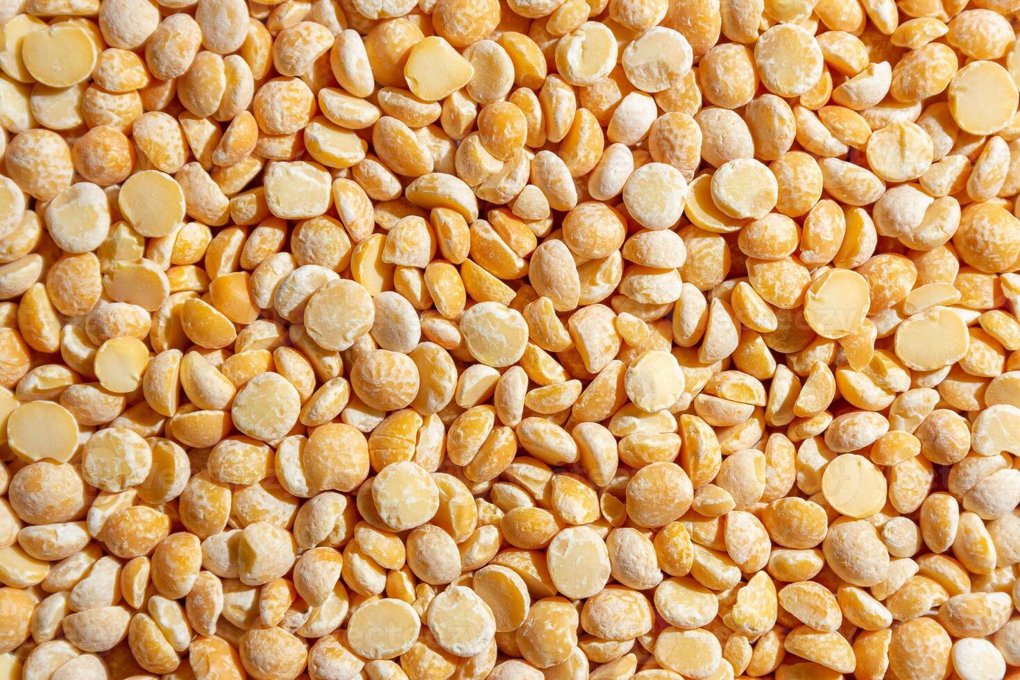 Uncooked Polished Split Peas Background. A Culinary Canvas of Dry Yellow Peas, Creating a Lively and Textured Background for Gourmet Cooking. Scattered Raw Polished Peas. Healthy Eating Ingredients photo