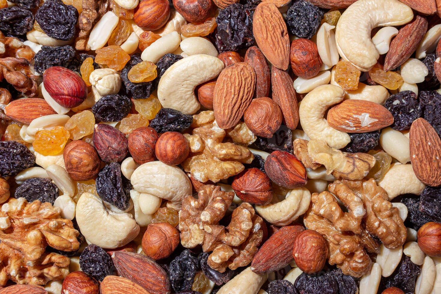 Mixed Nuts. Almonds, Walnuts, Cashews, Peanuts, Hazelnuts, Dried Prunes and Raisins. Different Nut Mix. Background from Various Nuts and Dried Fruits photo