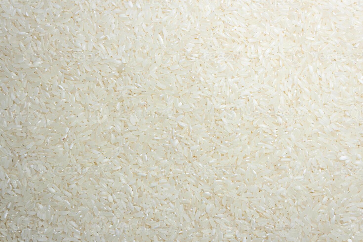 Dry Uncooked White Rice Background - Top View, Flat Lay. Scattered Raw Long Grain Rice. Asian Cuisine and Culture. Healthy Eating Ingredients. Diet Food photo