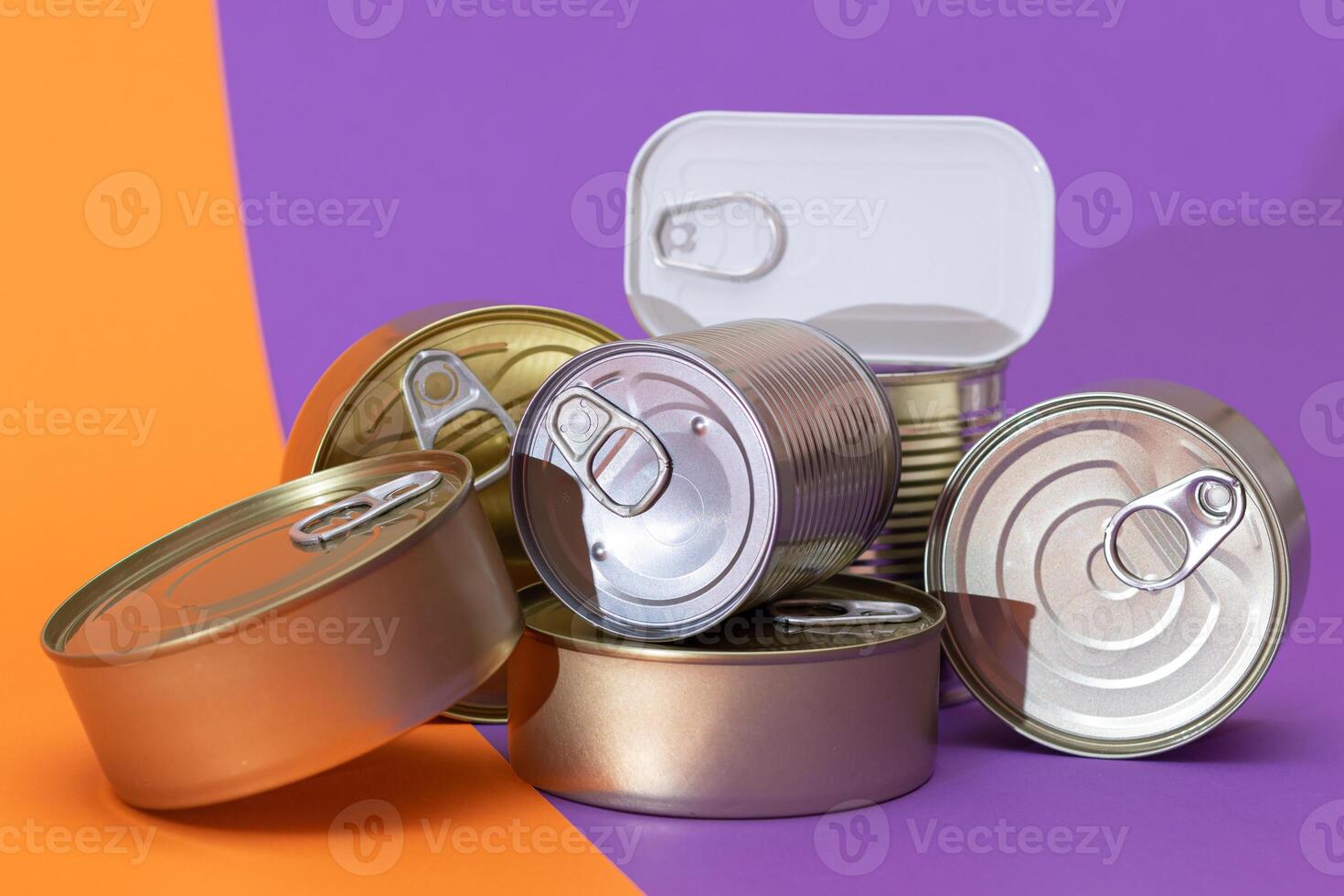 A Group of Stacked Tin Cans with Blank Edges on Split Orange and Violet Background. Canned Food. Different Aluminum Cans for Safe and Long Term Storage of Food. Steel Sealed Food Storage Containers photo