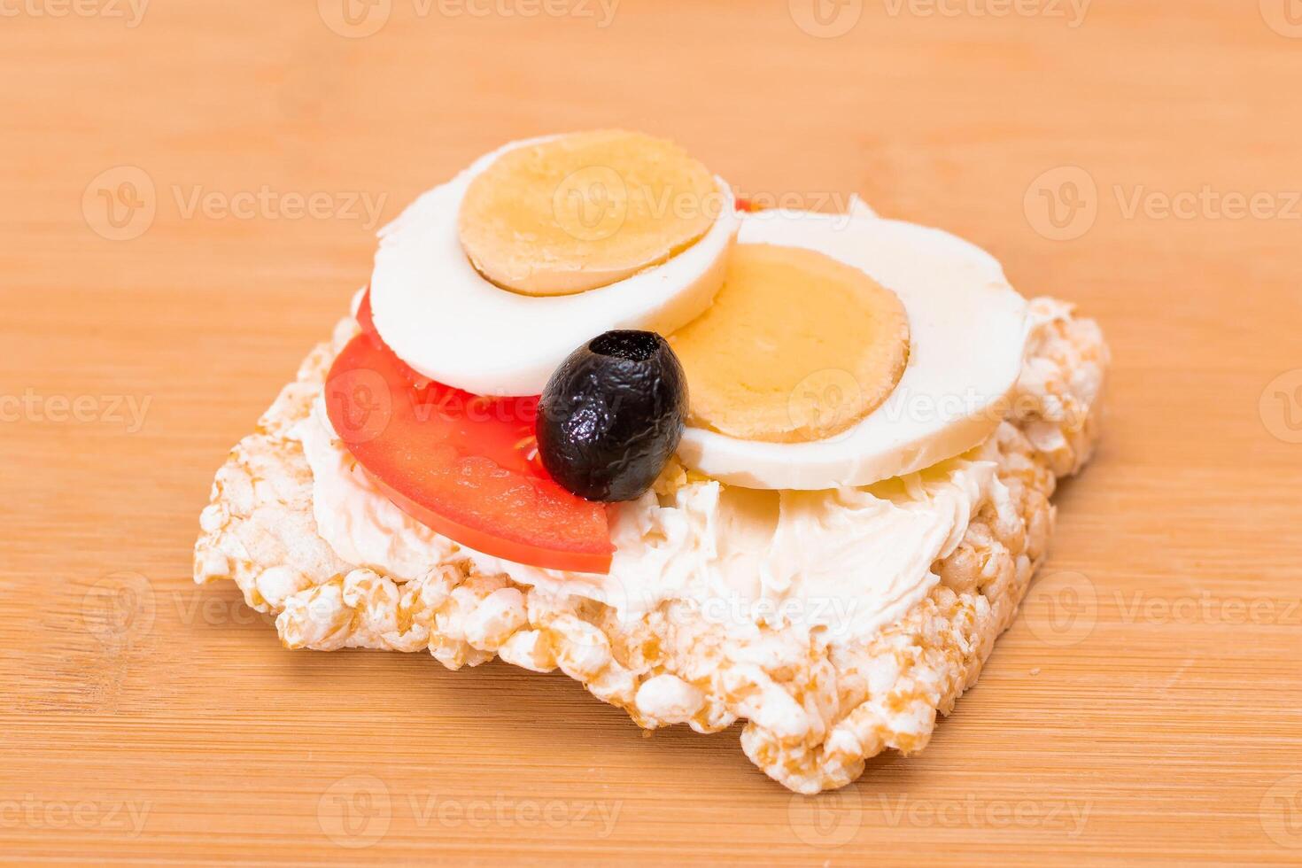 Rice Cake Sandwich with Tomato, Eggs and Olives on Bamboo Cutting Board. Easy Breakfast. Diet Food. Quick and Healthy Sandwiches. Crispbread with Tasty Filling. Healthy Dietary Snack photo