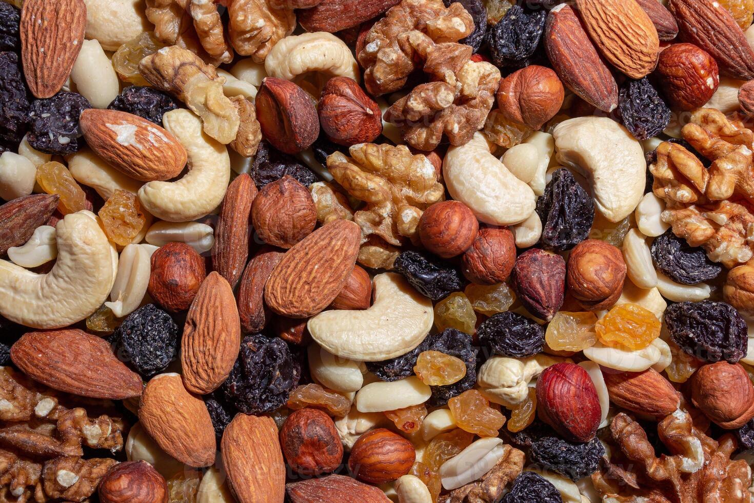 Mixed Nuts. Almonds, Walnuts, Cashews, Peanuts, Hazelnuts, Dried Prunes and Raisins. Different Nut Mix. Background from Various Nuts and Dried Fruits photo