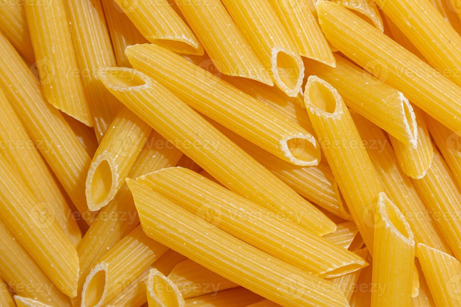 Uncooked Penne Rigate Pasta. A Culinary Canvas of Penne Macaroni, Creating a Lively and Textured Background for Gourmet Cooking. Dry Pasta. Raw Macaroni - Top View, Flat Lay photo