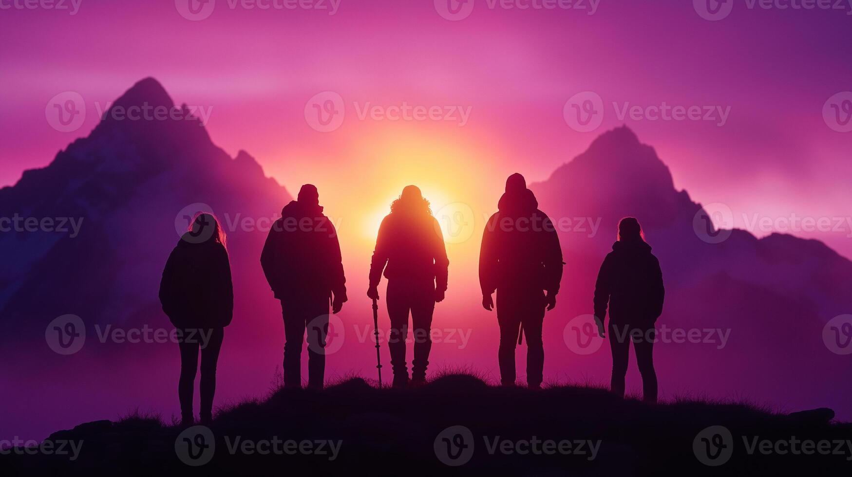 group of five hikers stands silhouetted against vibrant sunset, surrounded by majestic mountains. scene captures sense of adventure and camaraderie in natures beauty photo
