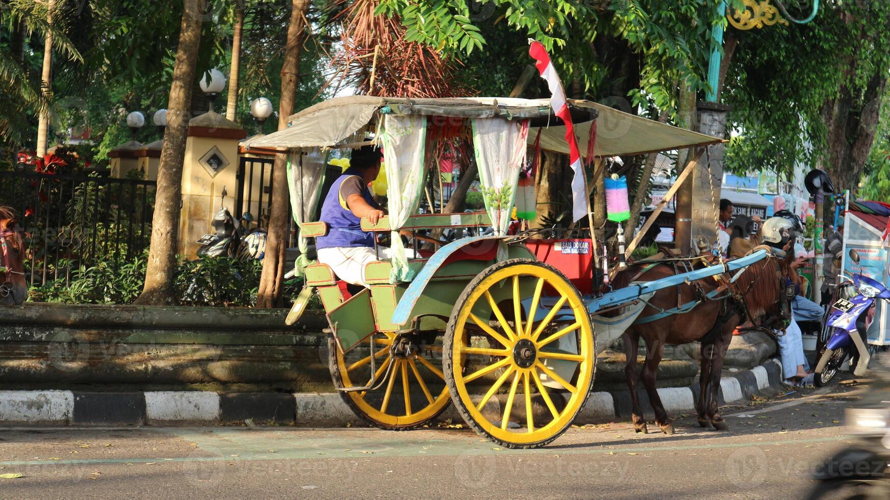 Salatiga, 18 Sept 2022 - coachman is waiting for passengers on the side of a city road. In Indonesia, the Delman is a traditional two-wheeled transportation vehicle that uses horse power. photo