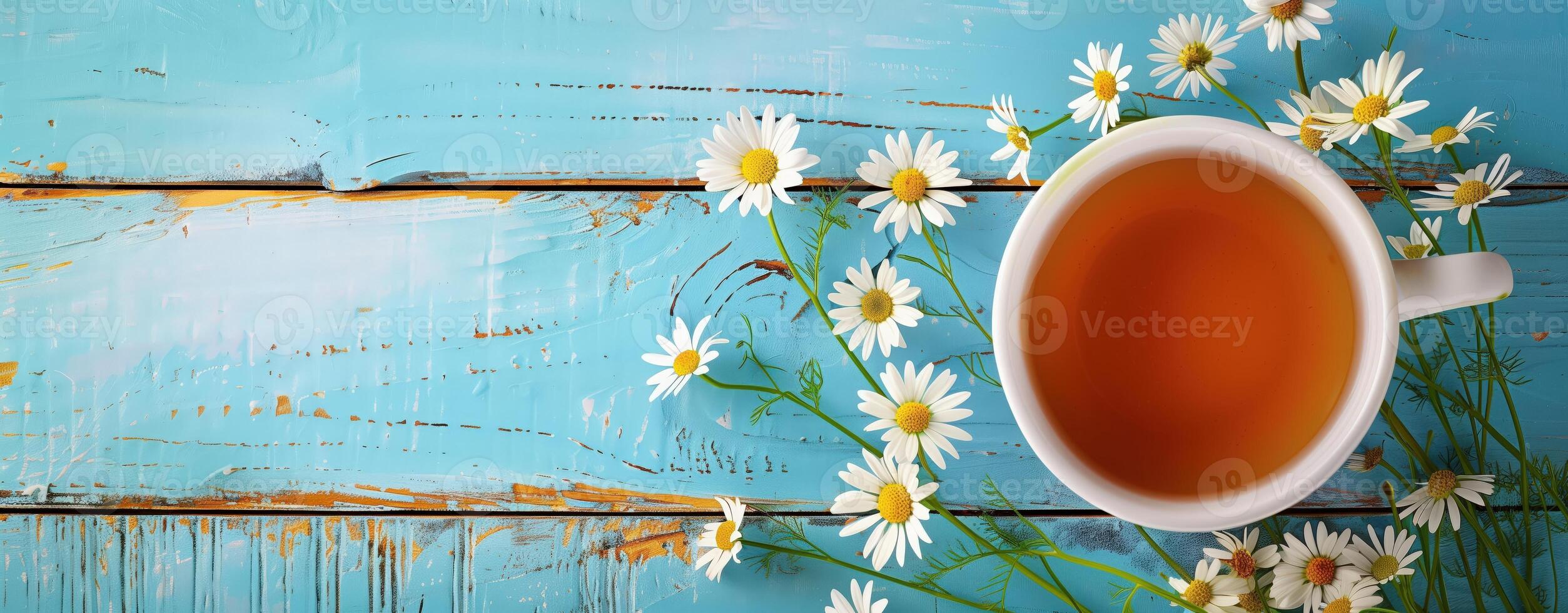 Cup of chamomile tea with fresh flowers on rustic blue wooden background, relaxing and wellness vibe photo