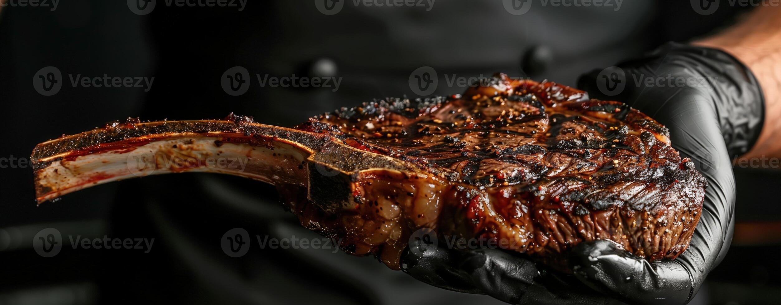 Chef's hand in a black glove holding a grilled tomahawk steak on a dark background for meat lovers photo