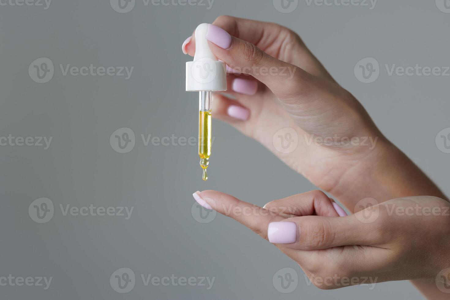 A beautiful young woman uses a facial serum. The girl applies the serum to her face with a dropper photo