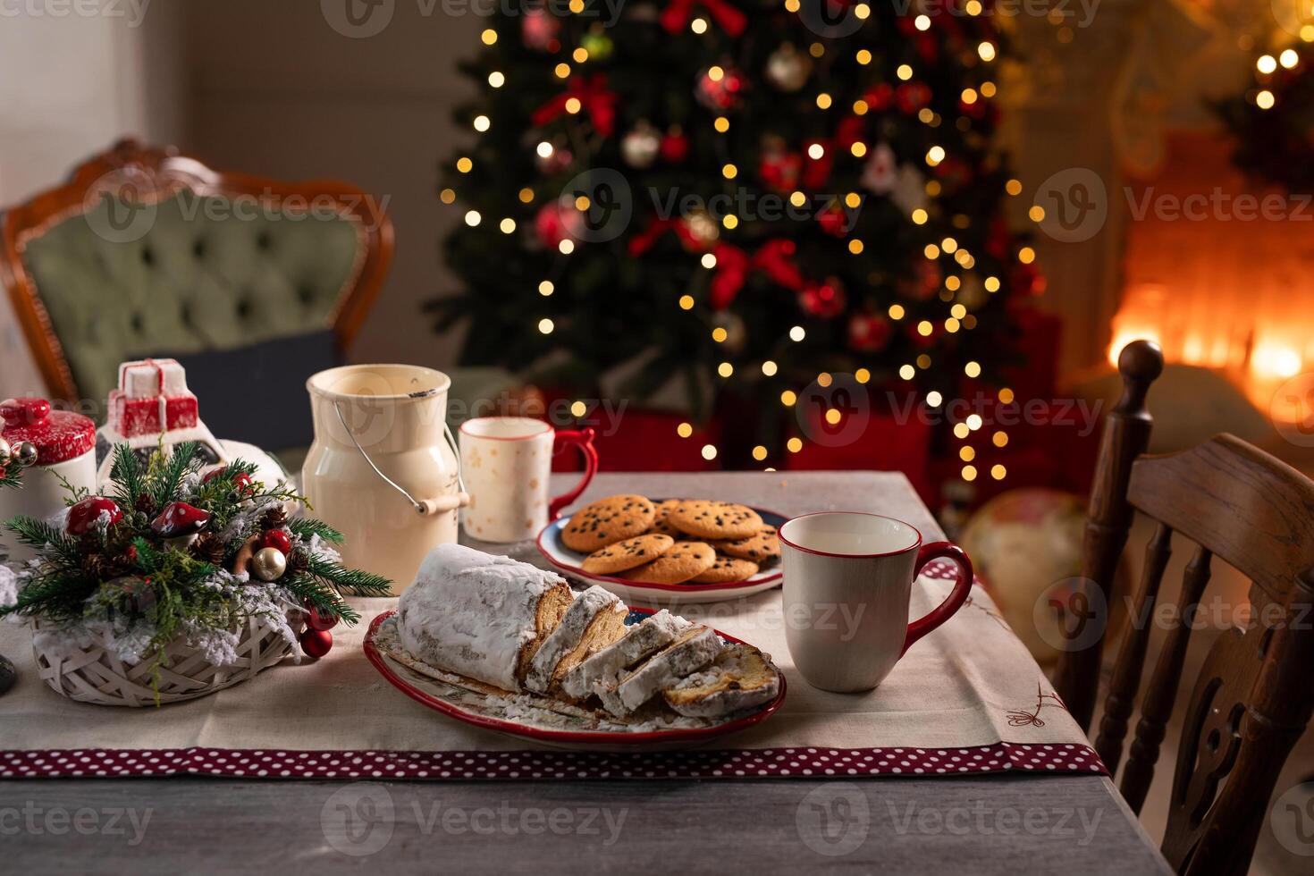 Christmas table with stollen cake, cups, cookies on the background of decorated Christmas tree and fireplace, Cozy Christmas atmosphere photo