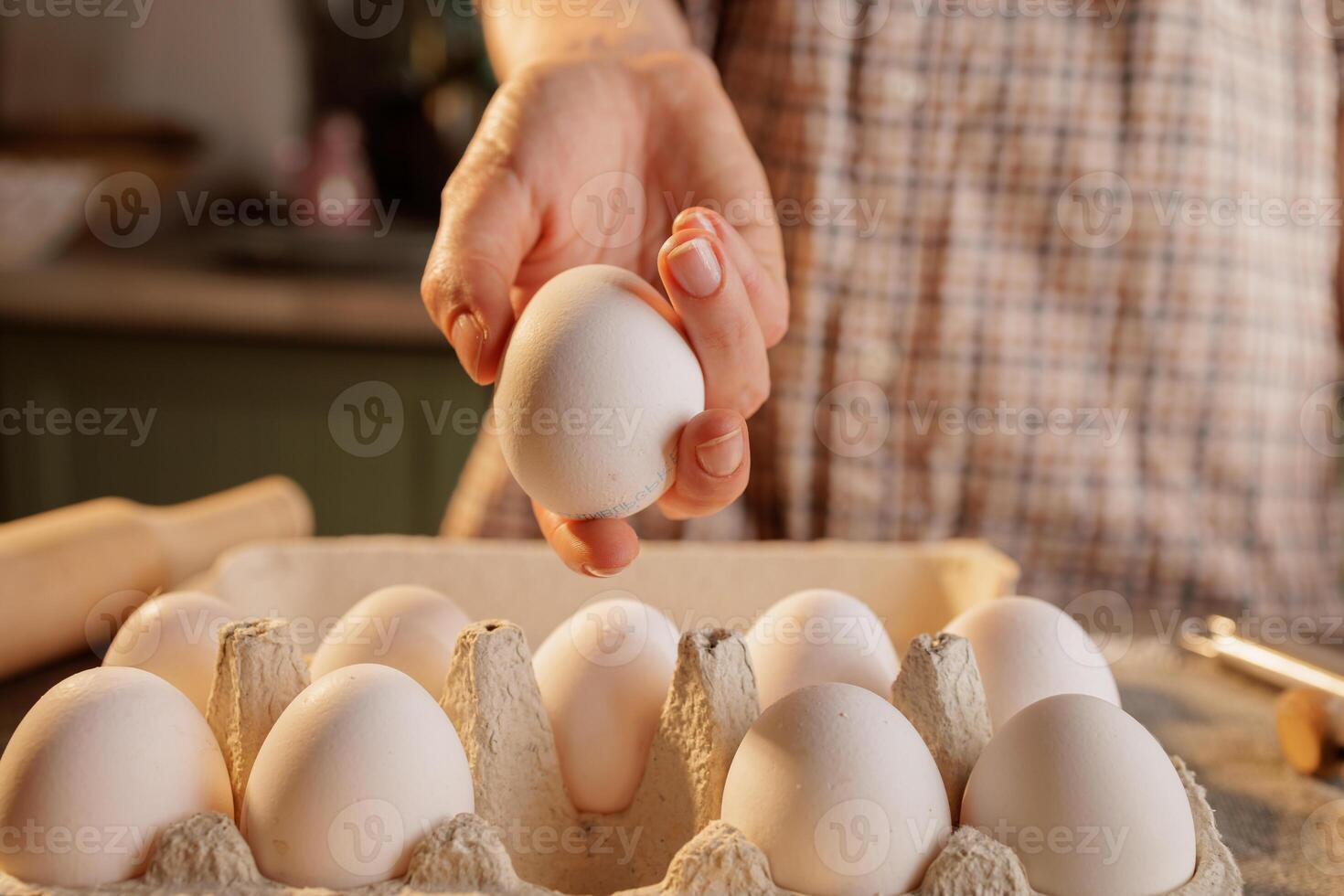 Heart shaped egg on frying pan, kitchen table and egg carton in background, top view photo