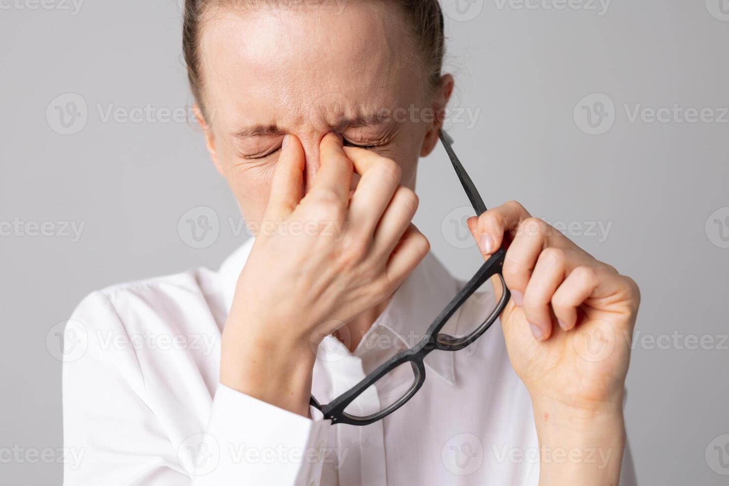 Woman taking off glasses and holding her eyes in pain, concept of optics and vision problems photo