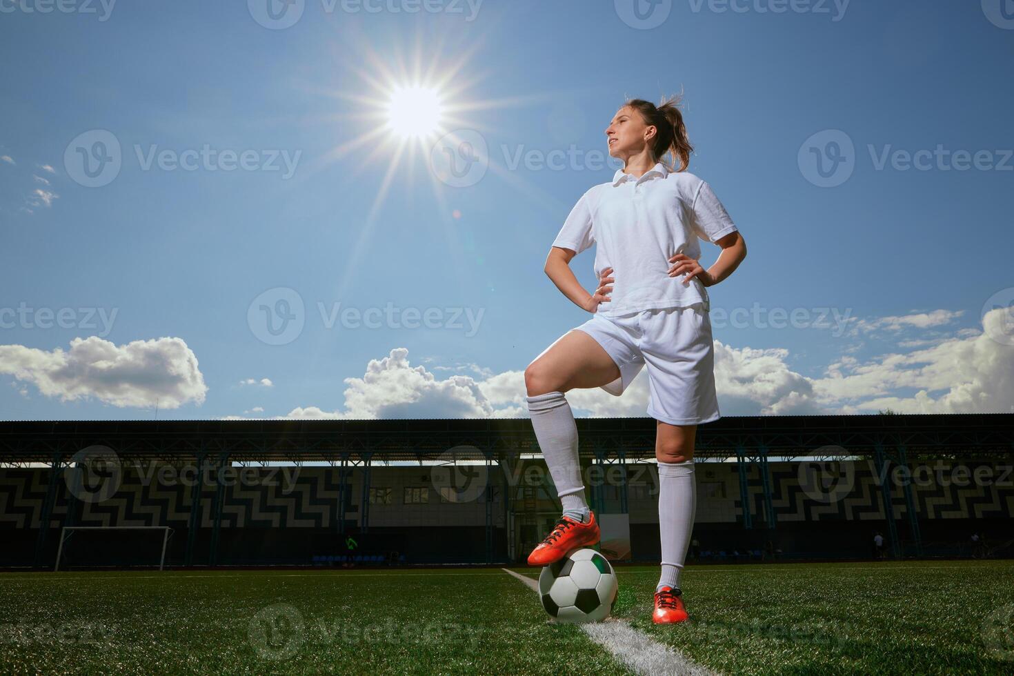 girl Football player in white shorts and red boots sets a soccer ball on a green field photo