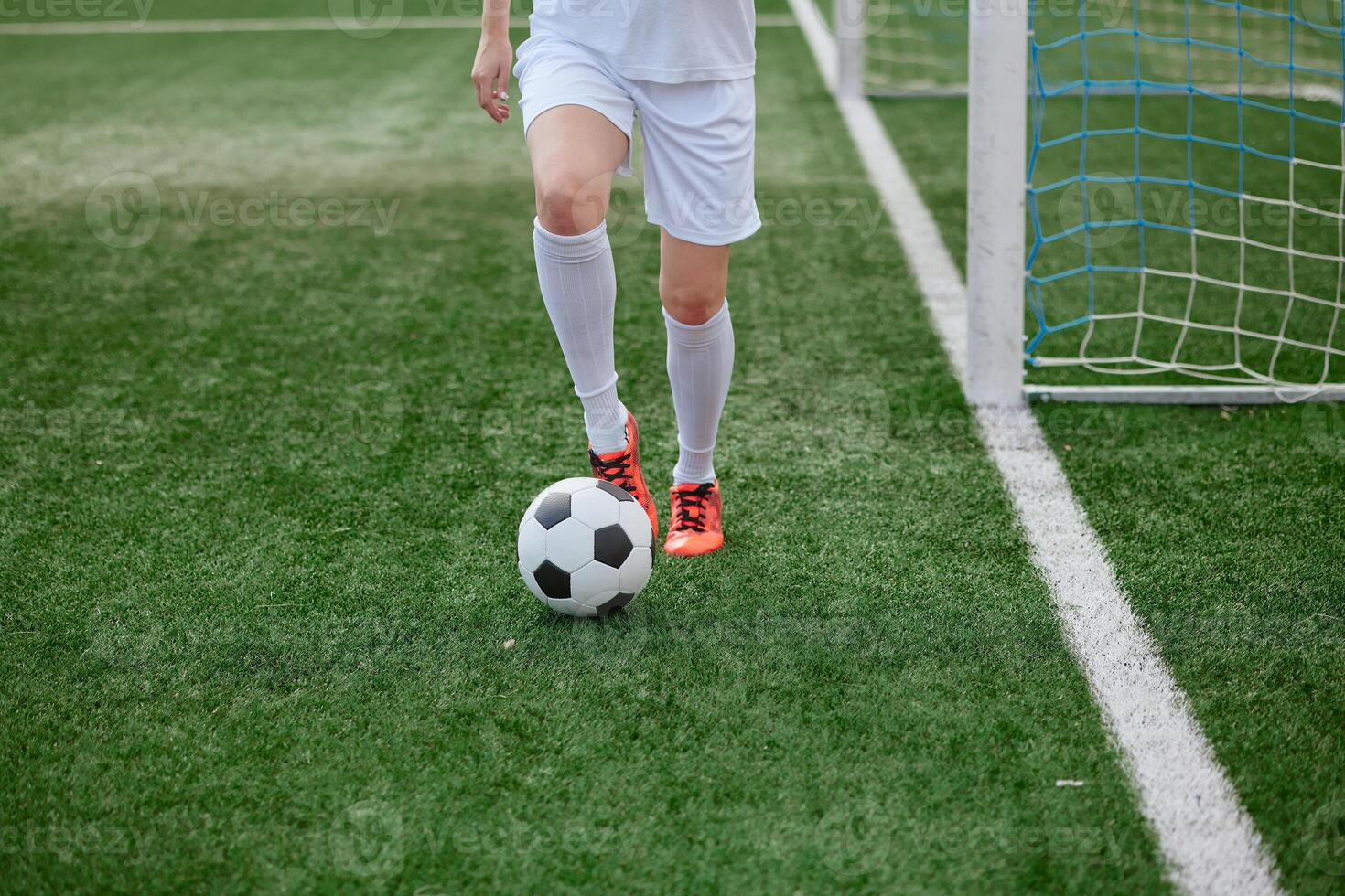 And the soccer player in the uniform and red clothes controlling the soccer ball on the Green Field photo