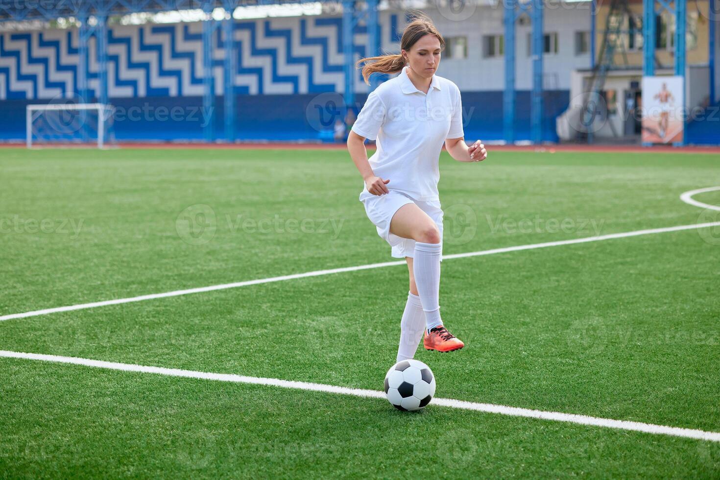 And the soccer player in the uniform and red clothes controlling the soccer ball on the Green Field photo