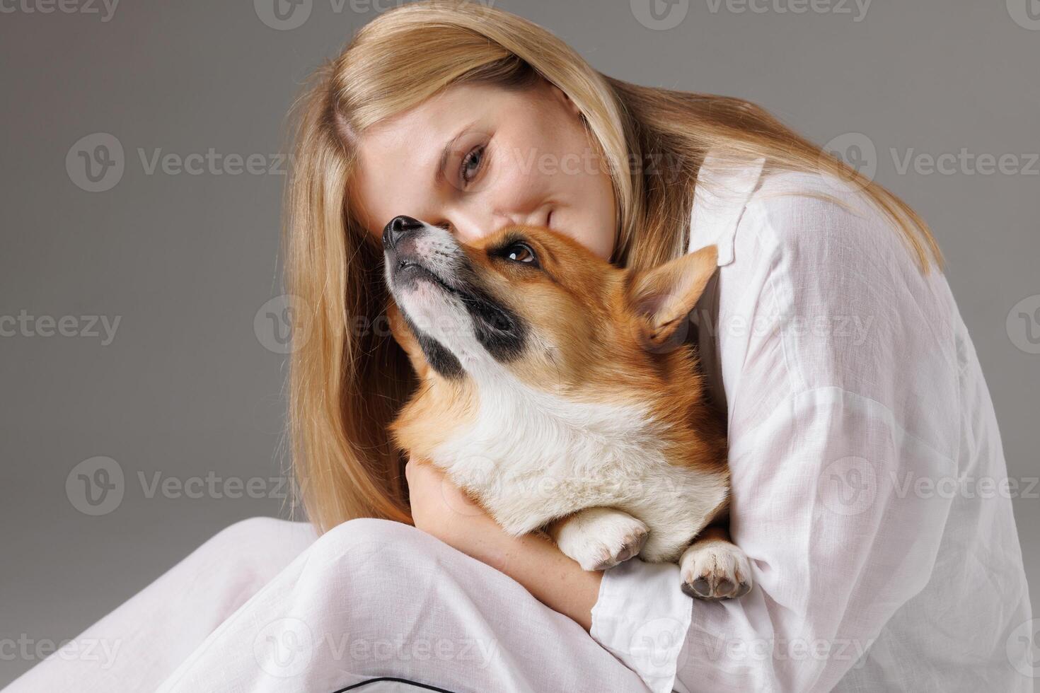Woman lovingly hugging corgi dog, isolated on white background photo