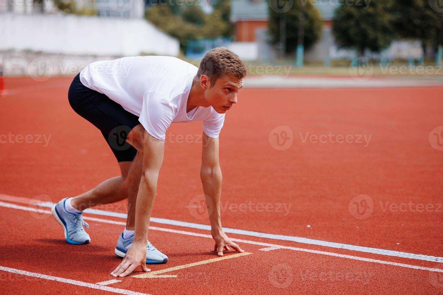 Male athlete in starting position on running track photo