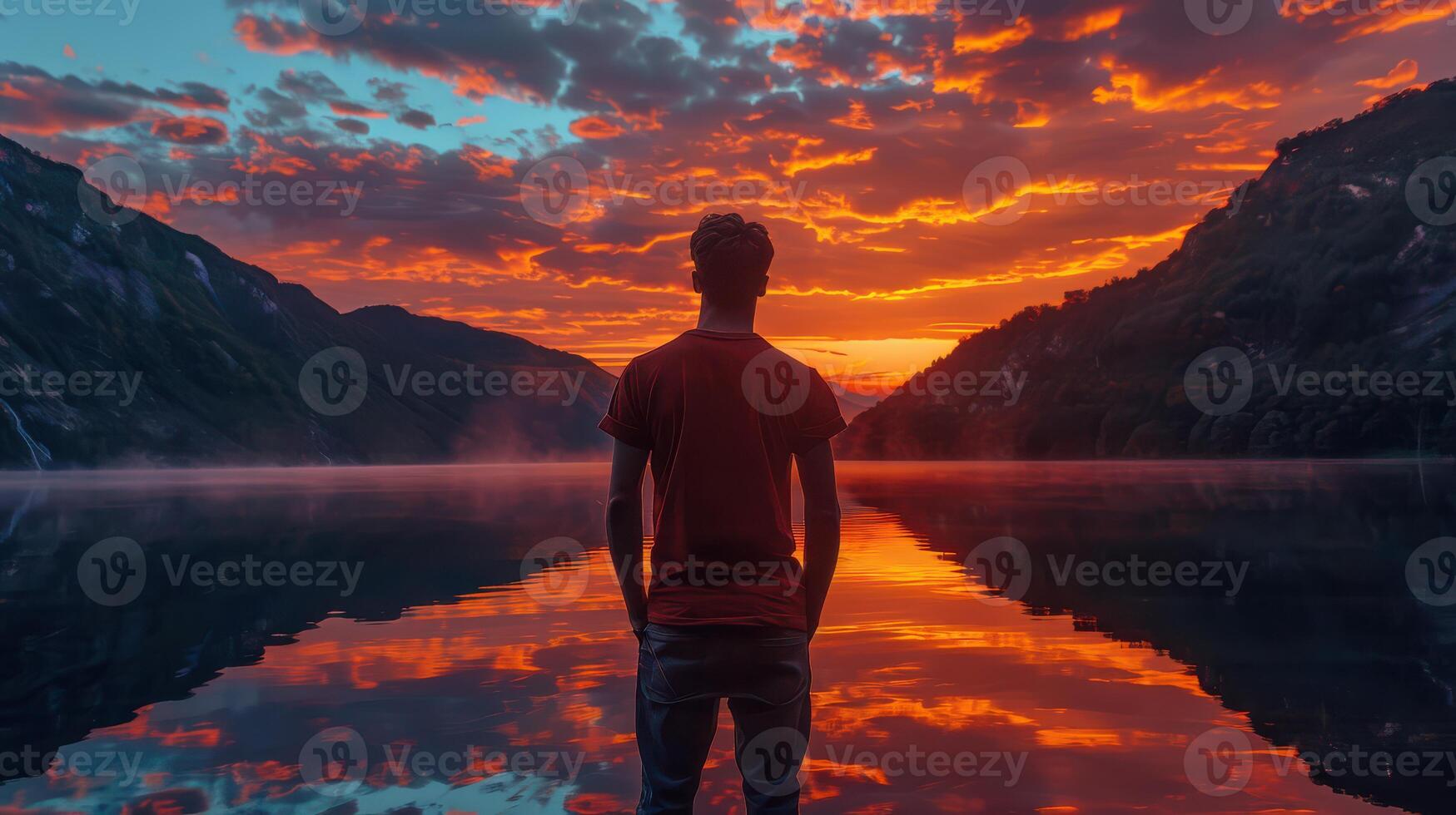A man standing in front of a lake at sunset photo