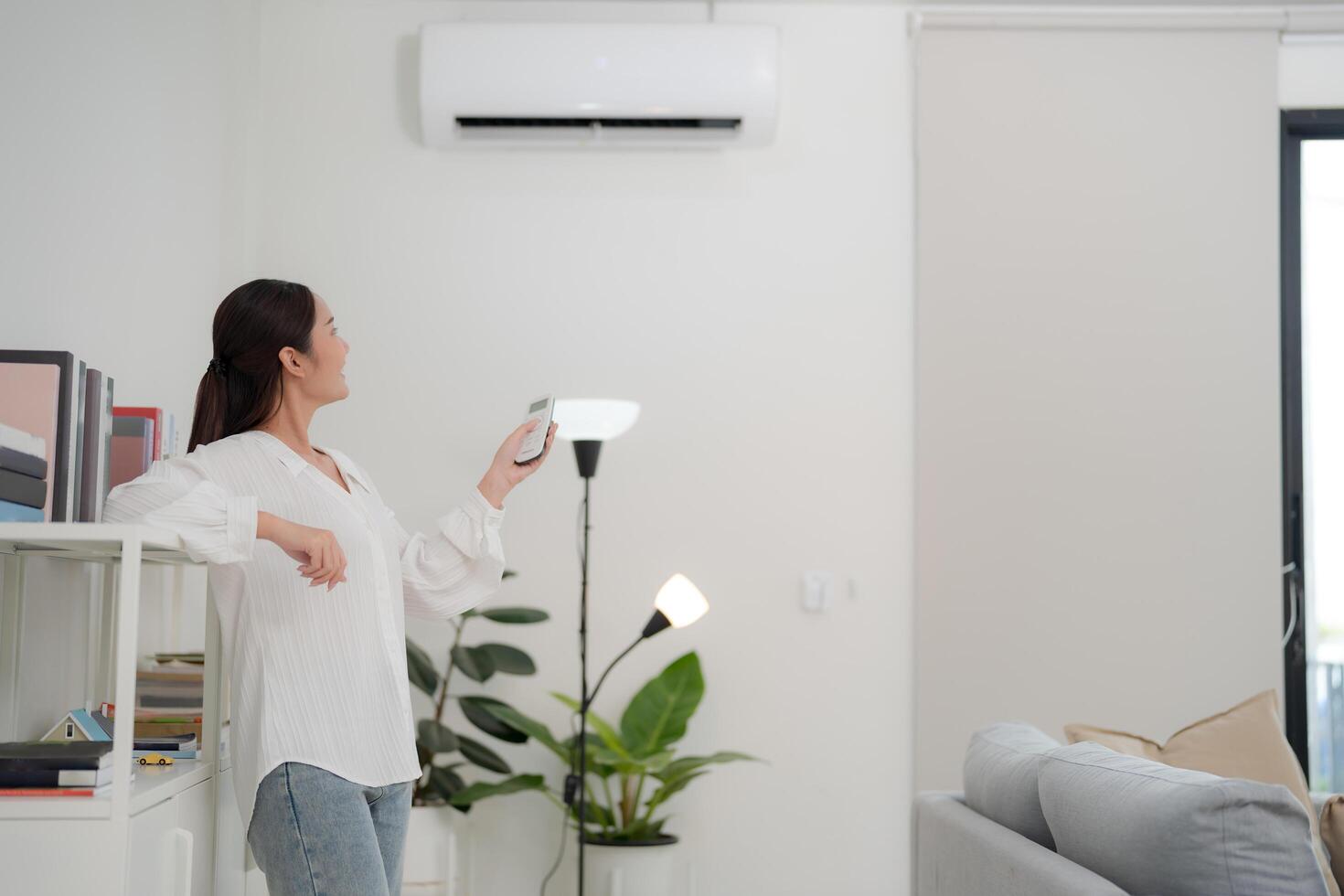 Young woman controlling smart air conditioning system at home photo