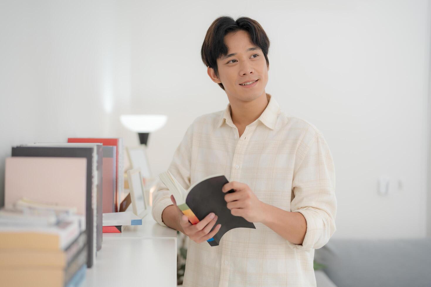 Young man reading in a bright living room photo