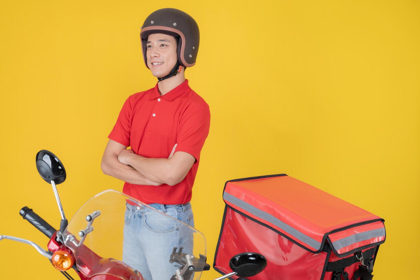 Confident delivery man with motorcycle on yellow background photo