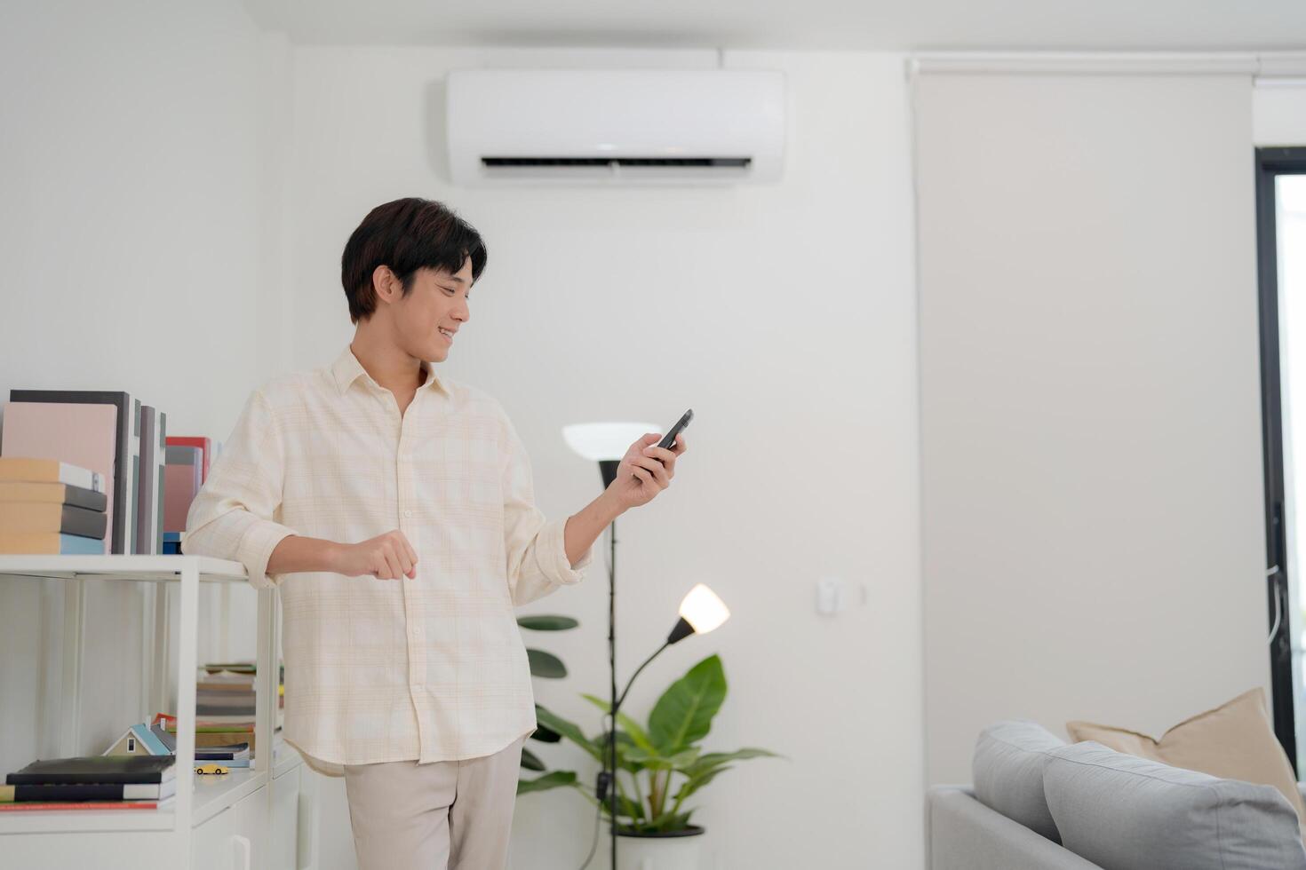 Young man using smart thermostat app in modern living room photo