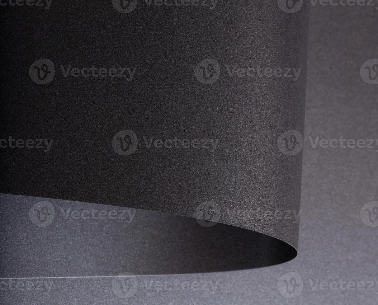 Black paper with a rich texture and minimalist monochrome background. The design features bent and photo
