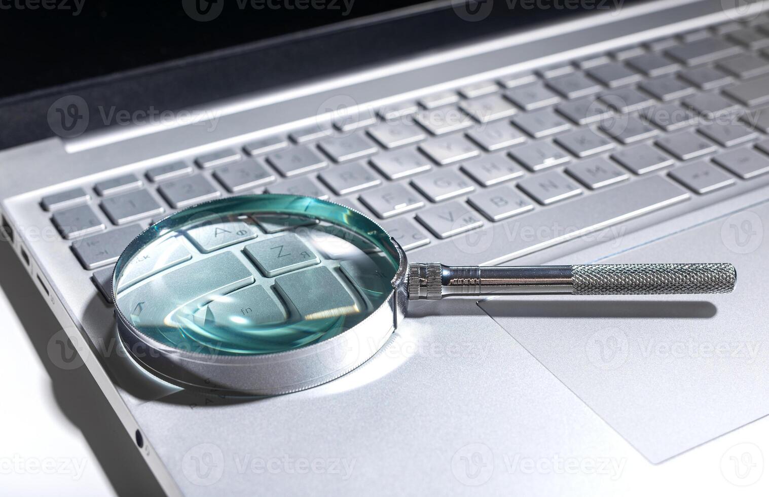 Laptop with glass magnifying tool, searching website data. SEO and digital research concept on white photo