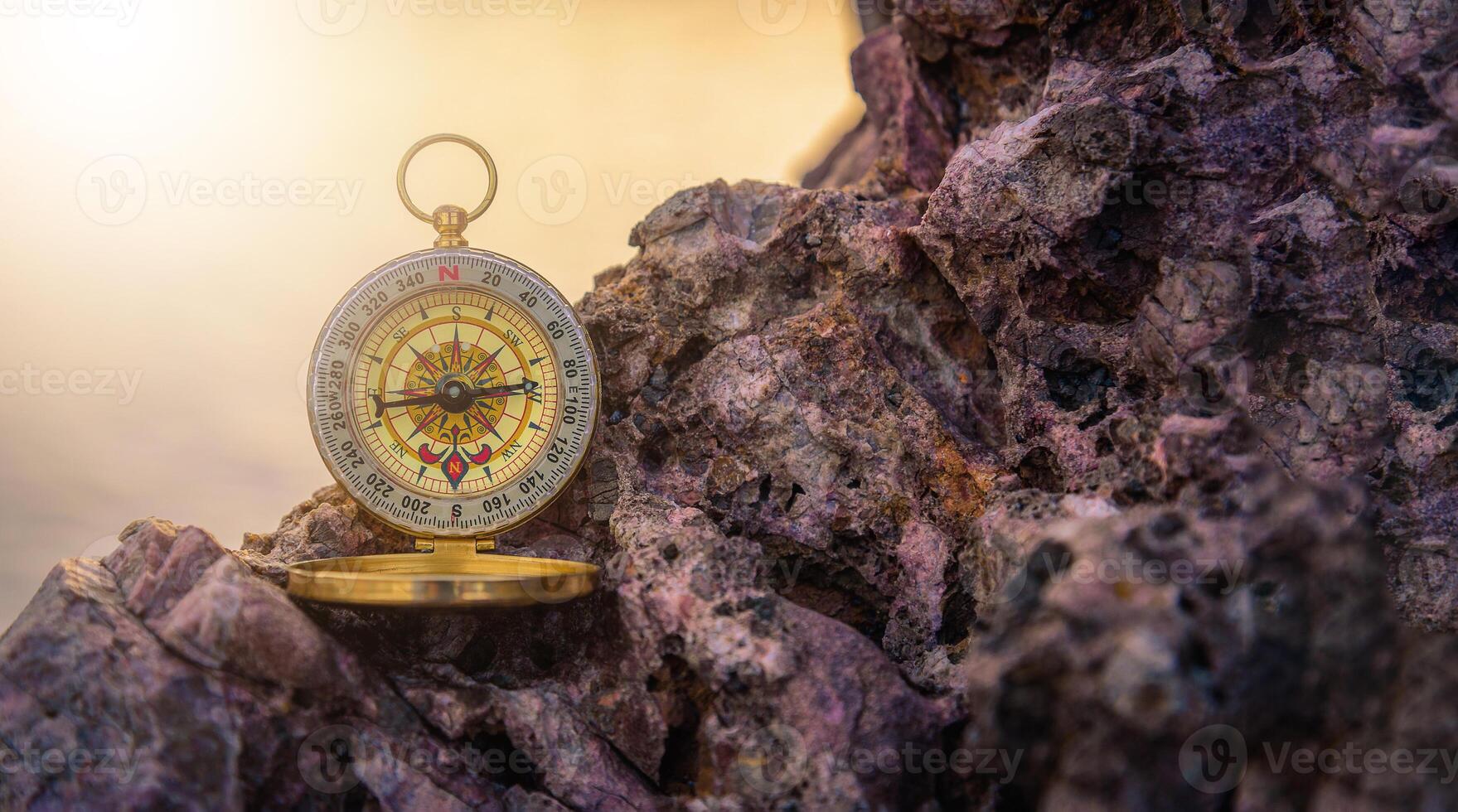 Analogical compass abandoned on the rocks with blurred sea background. photo