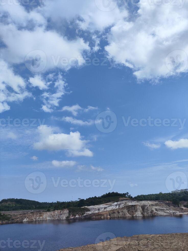 A man standing on a hill overlooking a lake photo